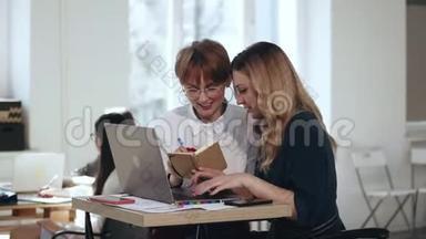 漂亮的年轻金发老板女人，用笔记本电脑工作，听同事在<strong>现代</strong>时尚的<strong>办公桌</strong>上笔记。